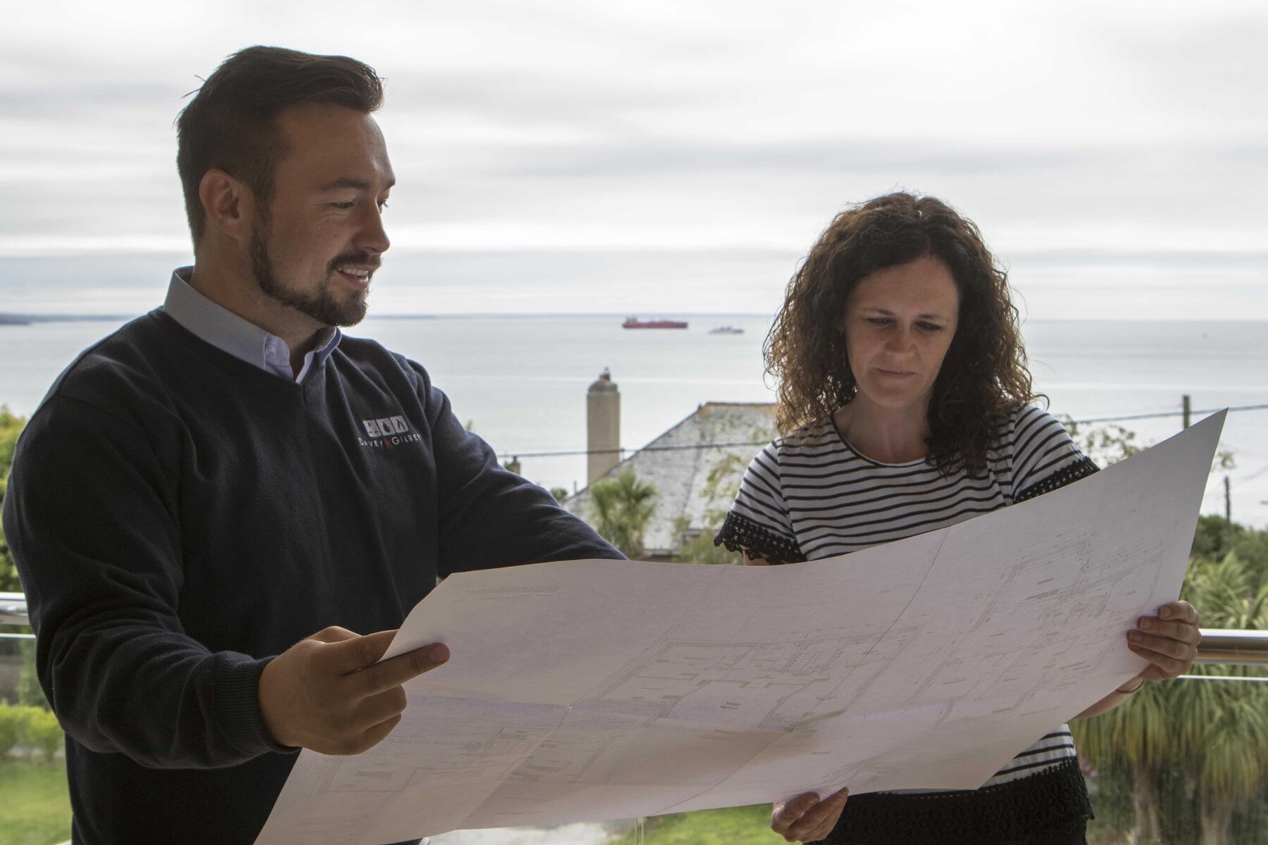 A Davey & Gilbert engineer reviewing drawings with a client by the coast
