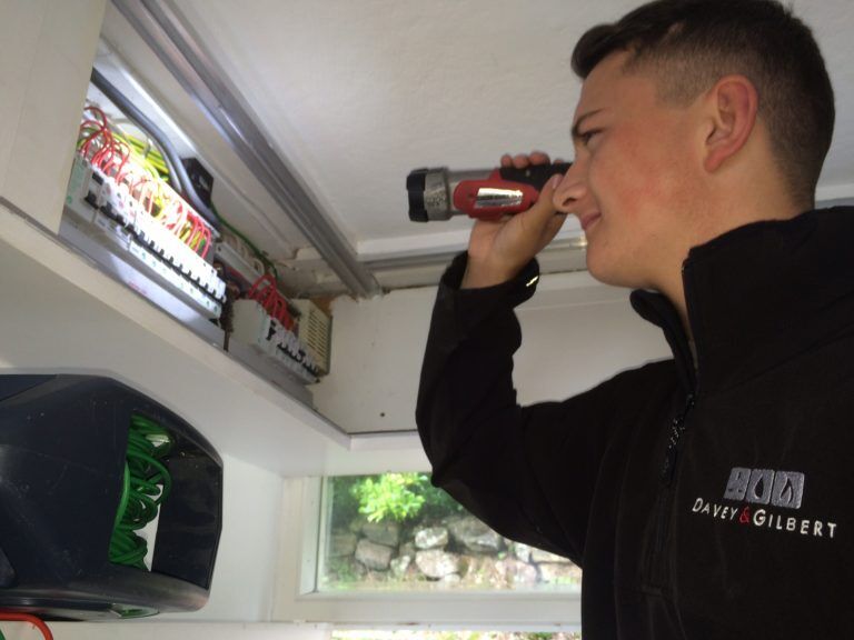 Engineer inspecting a consumer unit with a torch